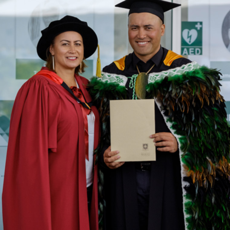 A woman in academic gown and a man in academic gown and kaakahu.